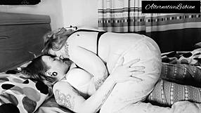 Two sexually different girls with tattoo draw closer and passionately kiss